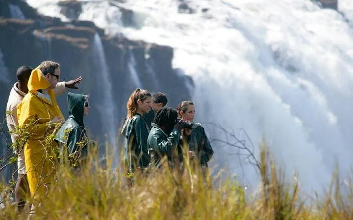 Tourists observing Victoria Falls from a viewpoint during a multi-day safari in Hwange National Park.
