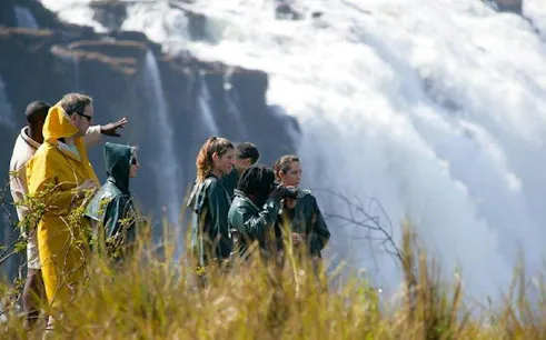 Tourists observing Victoria Falls from a viewpoint during a multi-day safari in Hwange National Park.