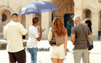 Tour group exploring Santo Domingo Colonial Zone with guide, near historic cathedral entrance.