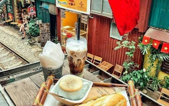 Hanoi street cafe with coffee, baguette, and view of train tracks on E-Scooter City Tour.