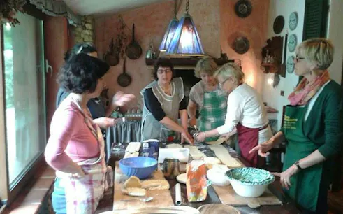 Pasta-making class participants at a farmhouse in Alghero, Italy, preparing dough with wine nearby.
