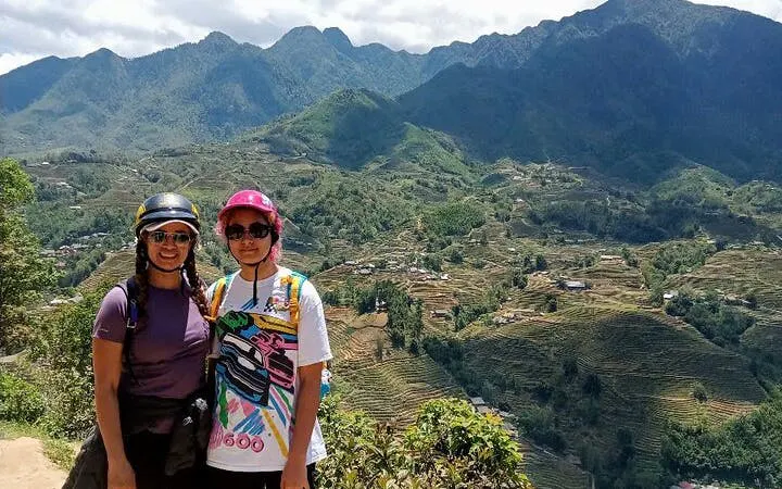 Two people on a motorbike tour overlooking terraced rice fields in Sapa, Vietnam.