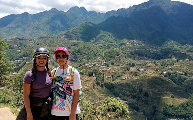 Two people on a motorbike tour overlooking terraced rice fields in Sapa, Vietnam.