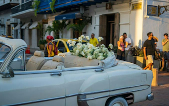Classic car with white flowers parked in Cartagena Walled City during a self-guided audio walking tour.