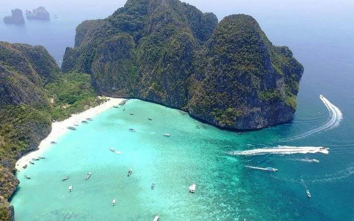 Aerial view of Banana Beach on Koh Hey with boats in turquoise water, Phuket day trip.