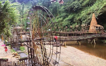 Bamboo water wheels and bridge in Sapa ethnic village, Vietnam, part of motorbike sightseeing tour.