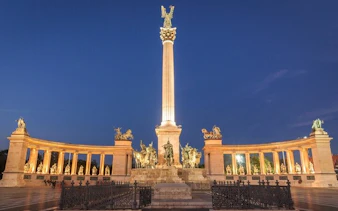 Heroes' Square in Budapest illuminated at night, part of the Ghosts of Budapest exploration game.