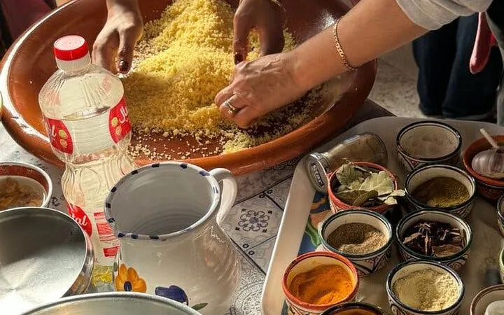 Hands preparing couscous with spices during a Moroccan cooking class in Essaouira.