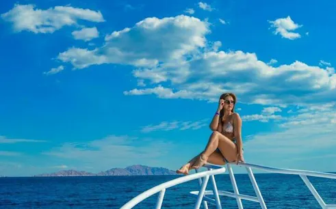 Snorkeler on boat deck with Ras Mohamed backdrop, Sharm el-Sheikh.