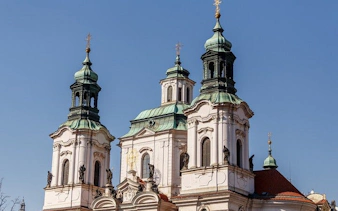 St. Nicholas Church towers in Prague under a clear blue sky.