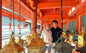Two people standing among hanging lanterns at Kasuga-taisha Shrine, Nara.