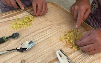 Hands chopping pasta dough during a cooking class in Bologna.