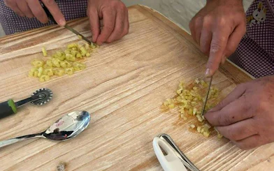 Hands chopping pasta dough during a cooking class in Bologna.