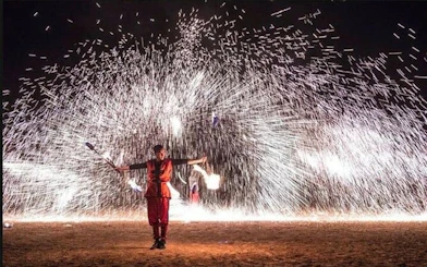 Fire performer at Chez Ali Folklore Show, Marrakesh, with sparks in the background.