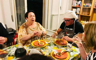 Dinner gathering with local chef and guests enjoying Sicilian cuisine and wine in Palermo.