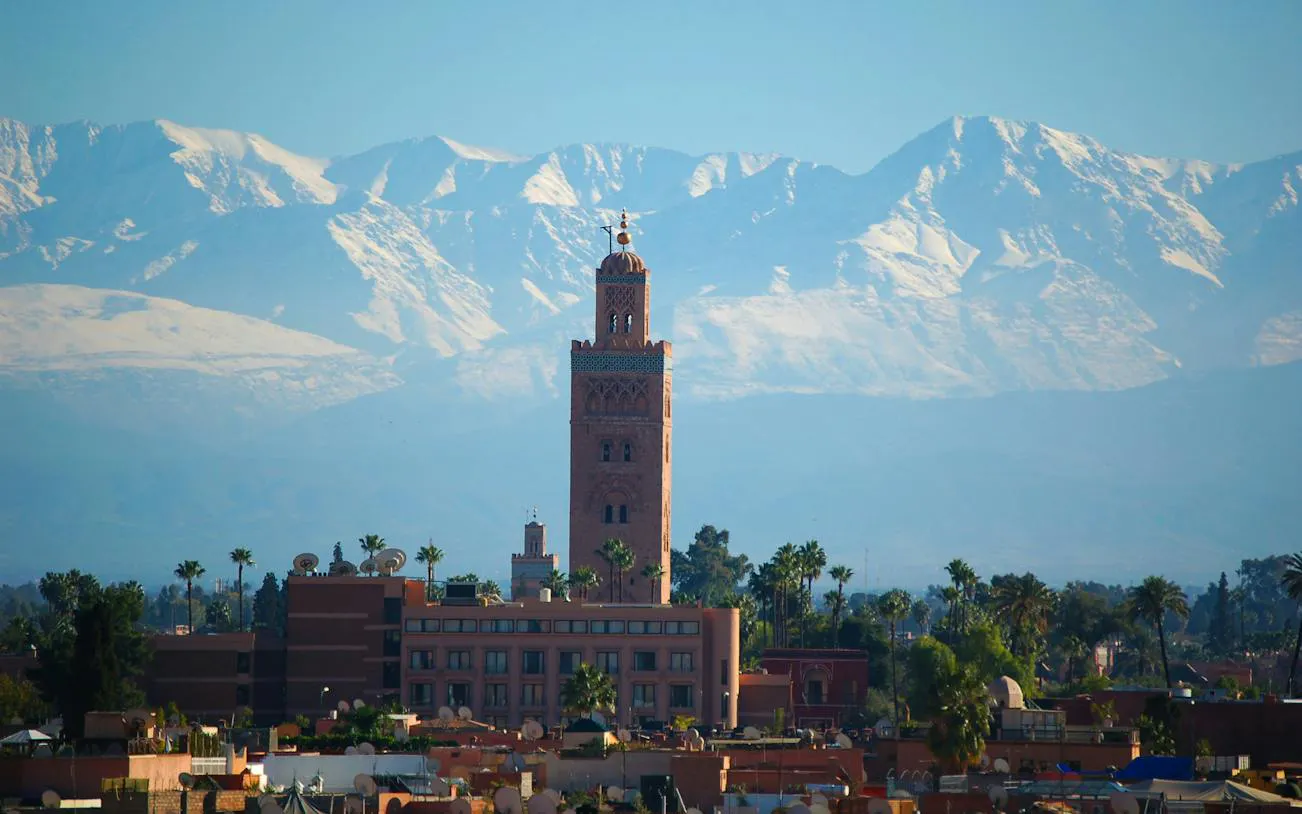 Koutoubia Mosque tower with Atlas Mountains backdrop in Marrakech Medina.