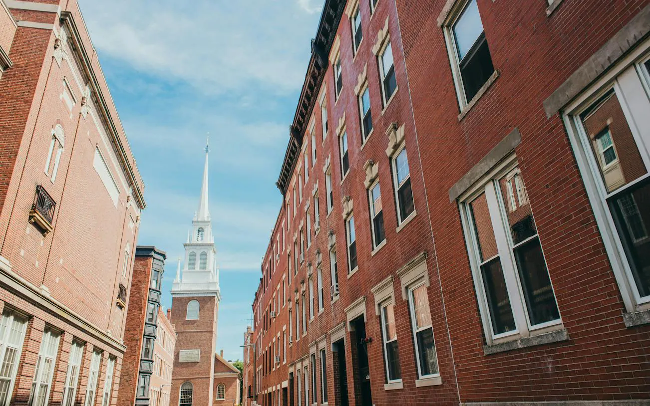 Old North Church along Boston Freedom Trail, viewed between historic brick buildings.