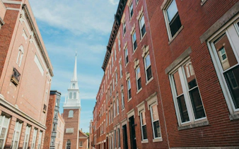 Old North Church along Boston Freedom Trail, viewed between historic brick buildings.