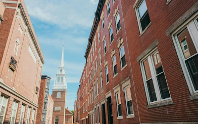 Old North Church along Boston Freedom Trail, viewed between historic brick buildings.