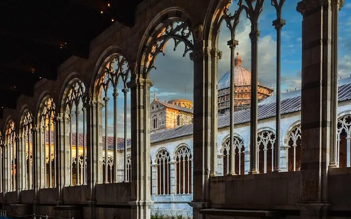 Leaning Tower of Pisa and Cathedral view through arches at sunset, Pisa, Italy.