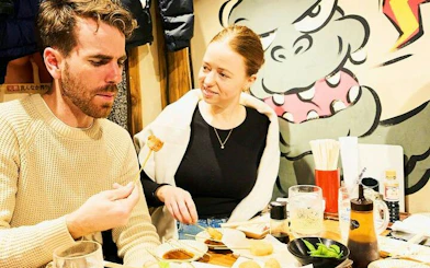 Couple enjoying skewers at a local eatery in Shinjuku during a guided food tour, Tokyo.