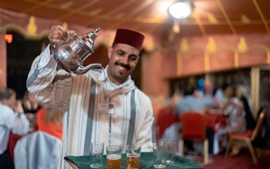 Server pouring traditional Moroccan tea at Chez Ali Folklore Show, Marrakesh.