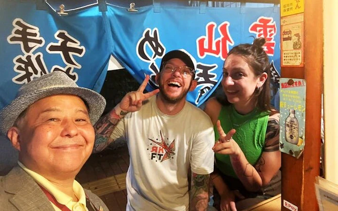 Tourists enjoying a food stall experience in Nakasu, Fukuoka with a local guide.