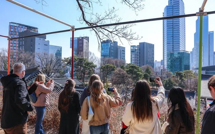 Tourists exploring Gangnam with city skyline and traditional architecture in Seoul.