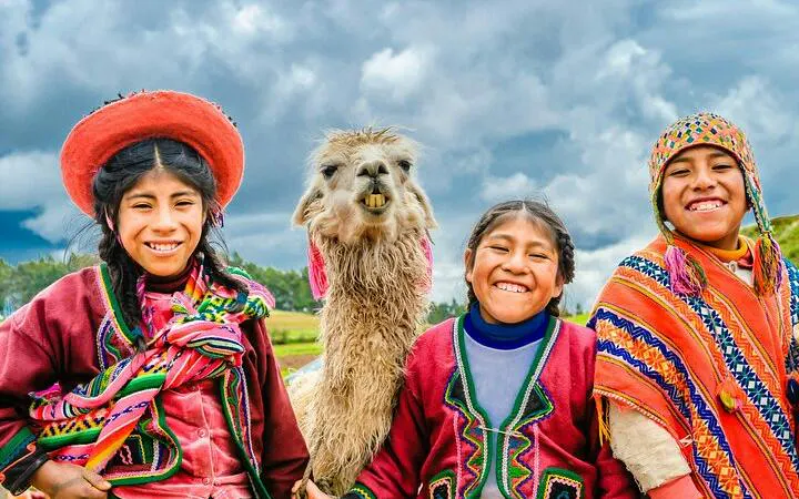 Children in traditional attire with a llama in Sacred Valley, Peru.
