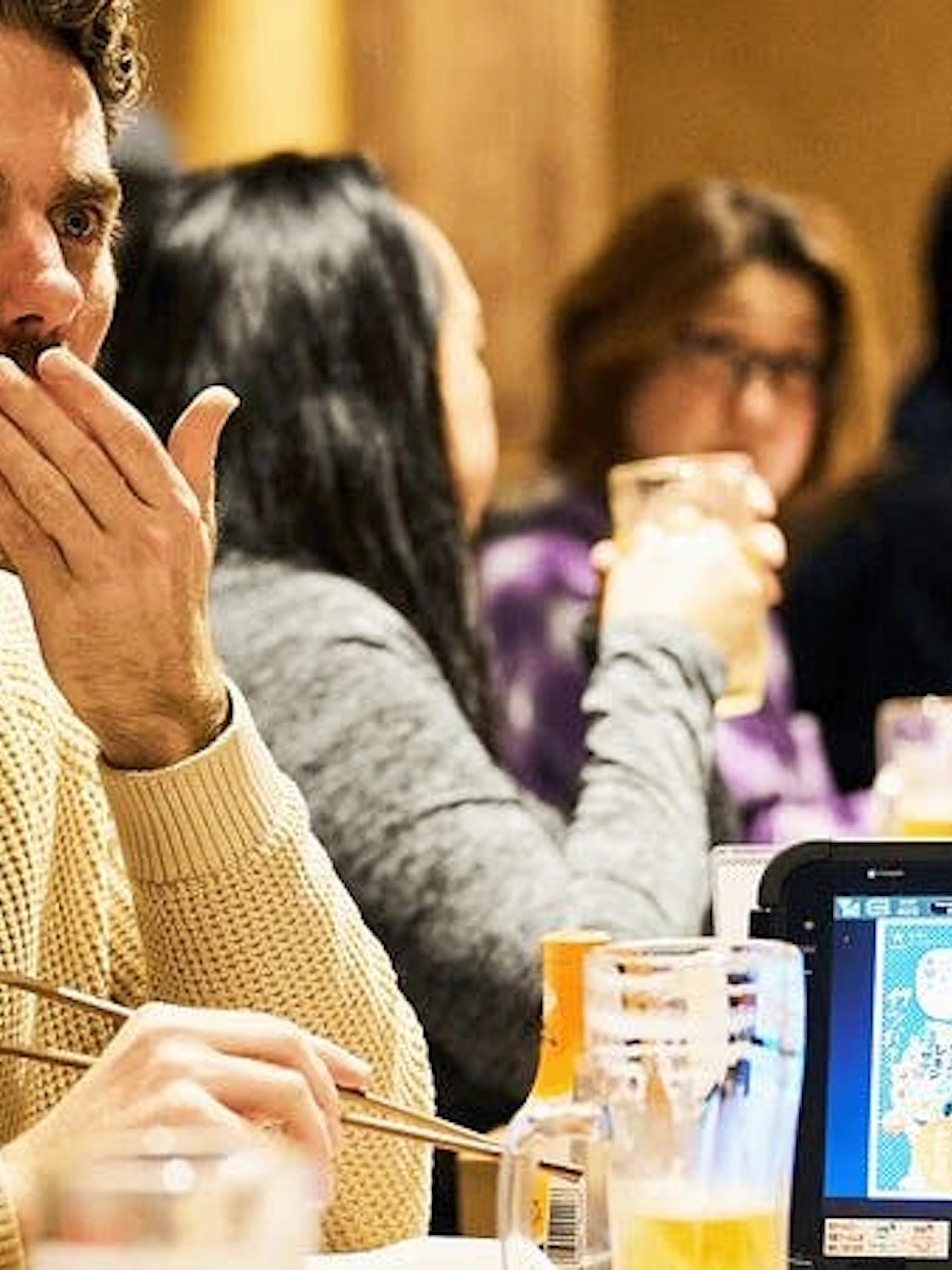 Dining group enjoying Osaka food tour with chopsticks and drinks.