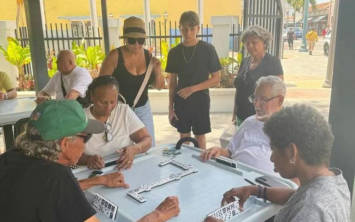 People playing dominoes at a table in Little Havana, Miami, during a guided walking tour.