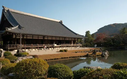 Temple with traditional architecture beside a pond in Arashiyama, Kyoto, during a private morning tour.