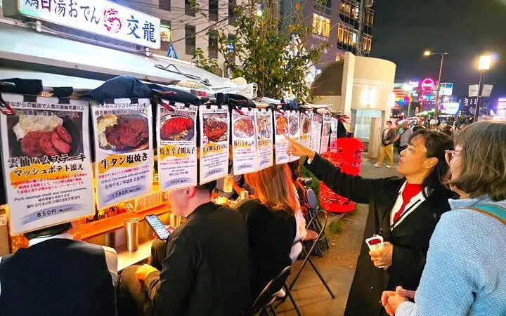 Nakasu food stall tour in Fukuoka with guide explaining menu to visitors.