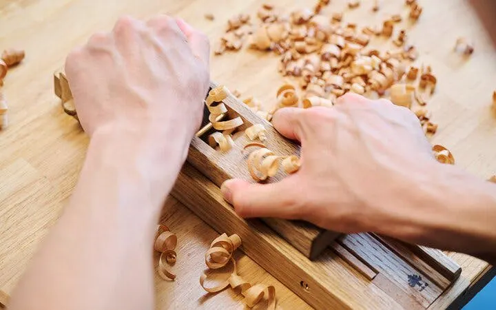 Hands crafting chopsticks at Kyoto Arashiyama workshop.