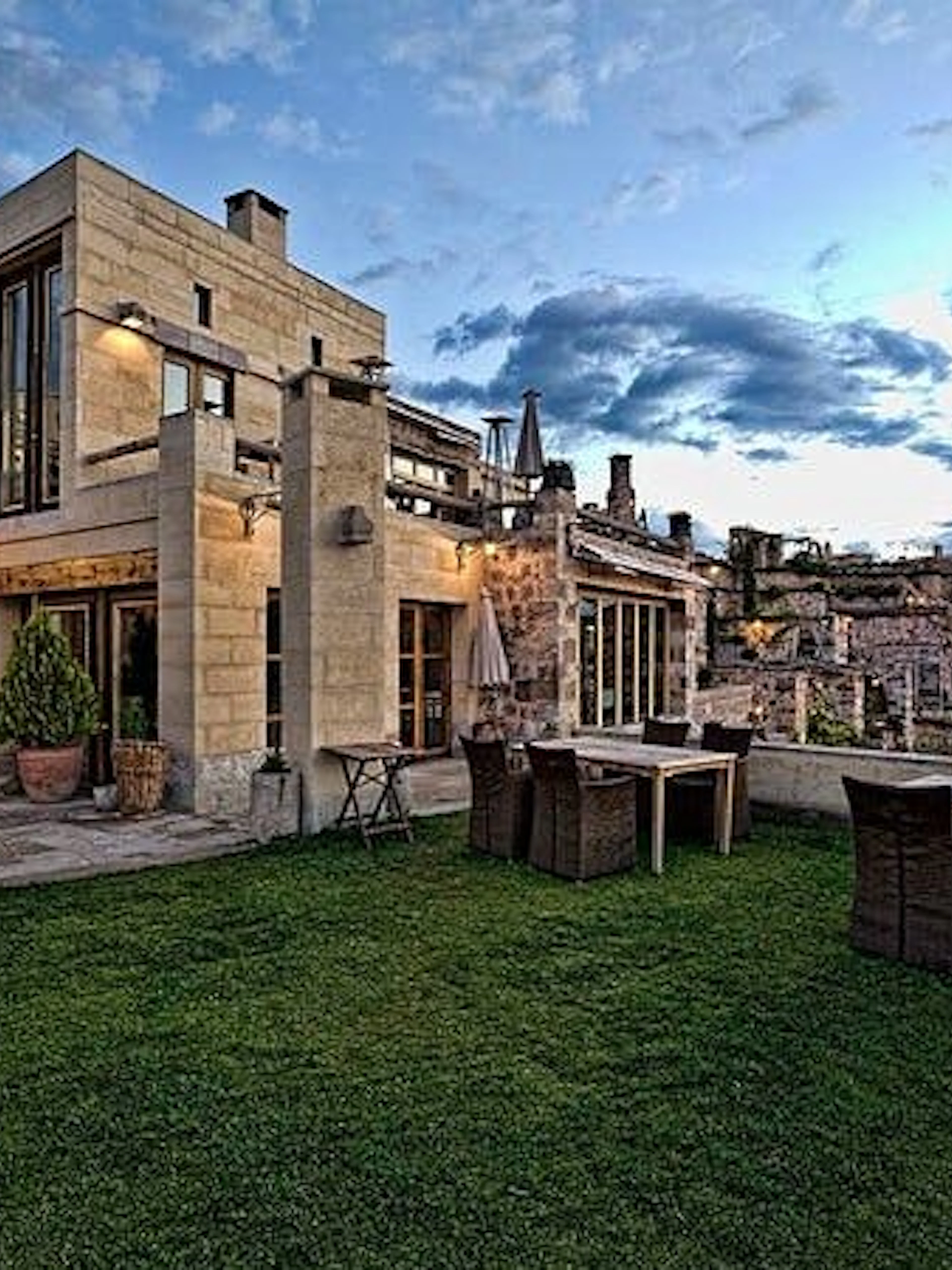 Cappadocia cave hotel terrace with stone architecture and outdoor dining area at sunset.