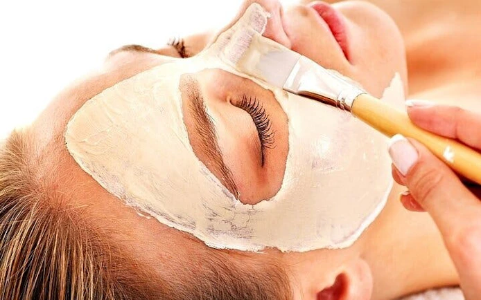 Applying facial mask during Moroccan Hammam ritual in Marrakesh bathhouse.