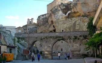 Cappadocia stone archway with tourists exploring historic site.