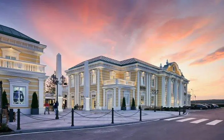 Parndorf Outlet shopping center at sunset during Budapest-Vienna private transfer.
