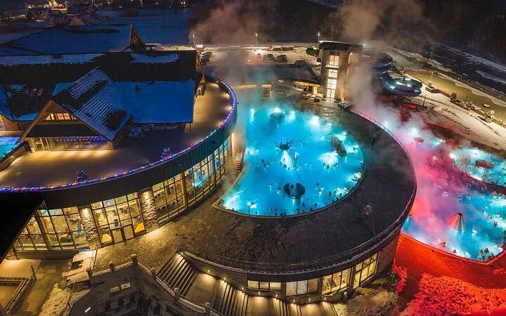 Chocholow Thermal Pools at night with steam rising, surrounded by snow.
