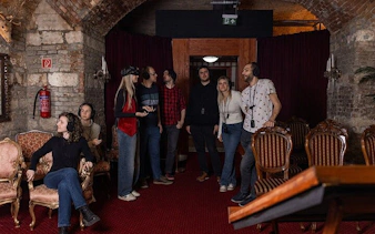 Visitors exploring Time Machine Budapest exhibition with VR headsets in a historic brick room.