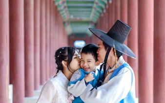 Family in traditional Hanbok at Seoul palace corridor during photoshoot.
