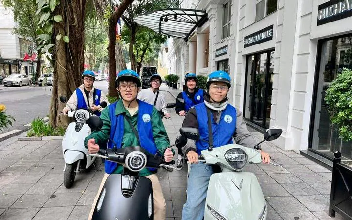 Group on e-scooters ready for Hanoi city tour with street food and drinks.