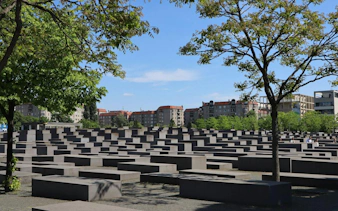 Holocaust Memorial in Berlin with concrete slabs and surrounding trees.