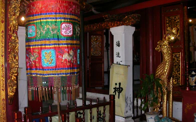 Colorful embroidered banner and golden statue in Hanoi Old Quarter temple.