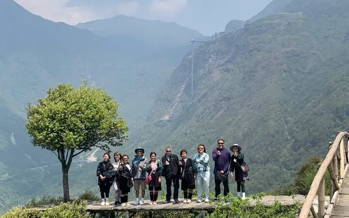 Group on a scenic Sapa motorbike tour with mountain backdrop and tree.