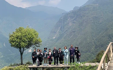 Group on a scenic Sapa motorbike tour with mountain backdrop and tree.