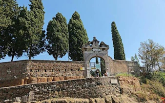 Appian Way entrance with ancient stone walls and cypress trees, Rome bike tour.