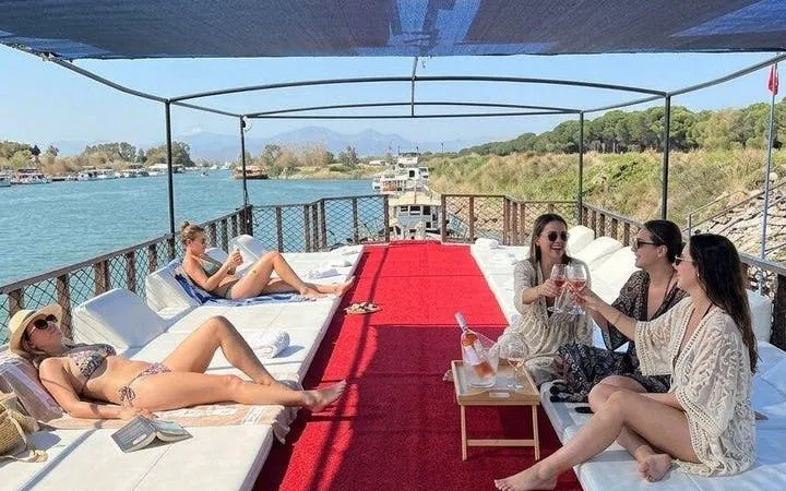 Boat tour in Antalya with people relaxing and enjoying drinks, surrounded by scenic river views.