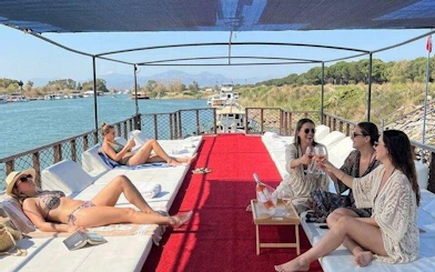 Boat tour in Antalya with people relaxing and enjoying drinks, surrounded by scenic river views.