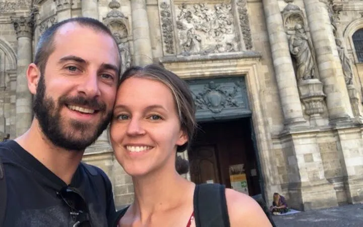 Couple in front of ornate stone facade in Old Town Bordeaux during self-guided city exploration game.